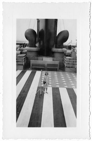 Nona Baldwin standing on deck of the SS Washington; the deck is painted with the U.S. flag