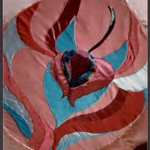 Textile work of organic, petal-like shapes in shades of red, pink, and teal