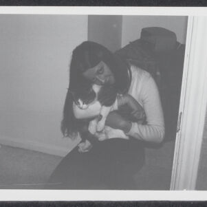 Black-and-white photograph of a kneeling woman holding a cat