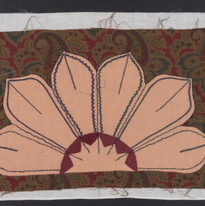 One half of a flower applique in pink and dark red on brown paisley fabric
