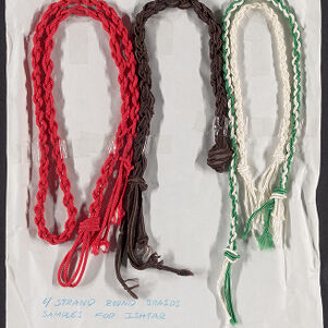 Four loops of braided cord in red, brown, white, and green taped to a white piece of paper with handwritten annotations in blue