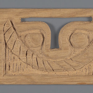 Carved wooden rectangle with abstract shapes in relief and two cutouts