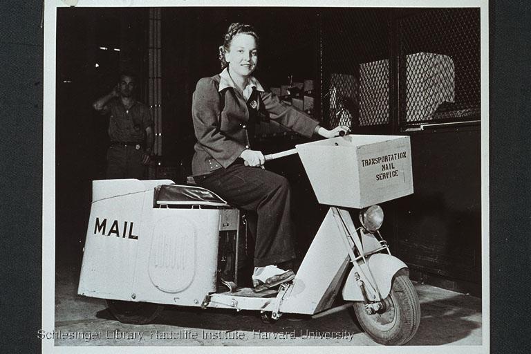 Woman postal clerk seated on a motorcycle outfitted for mail delivery
