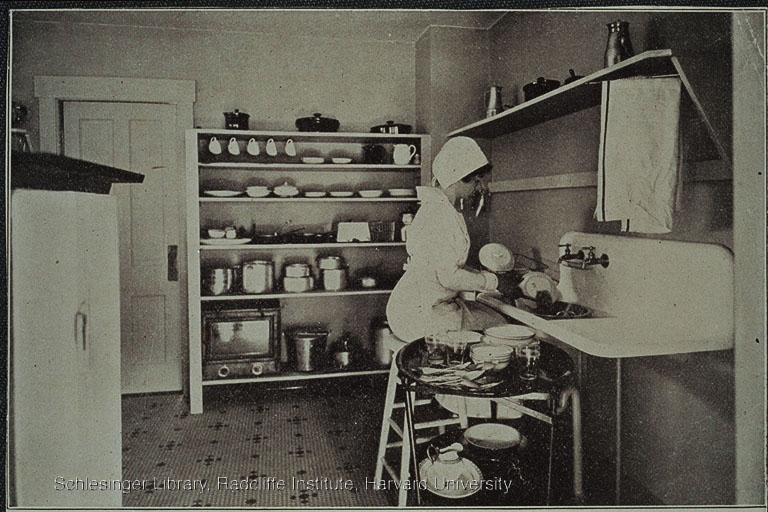 Portrait of a Christine Frederick washing dishes in an Applecroft Home Experiment Station kitchen.