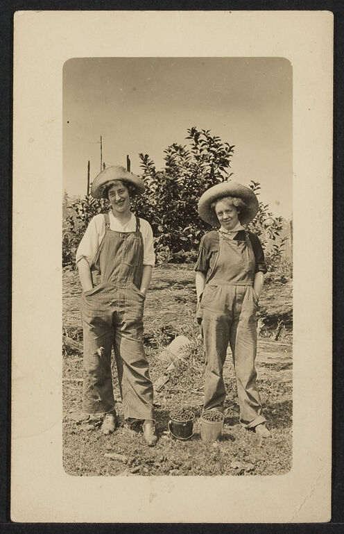 Two female farmers working in a field dressed in overalls