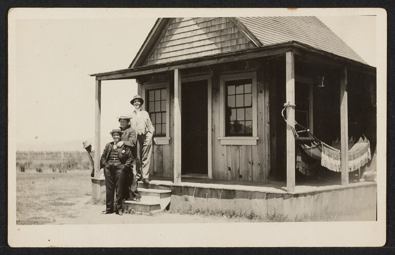 Three women dressed as men on the porch of a frontier house