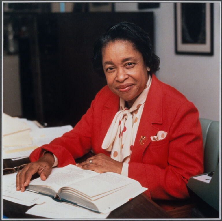 Margaret Walker Alexander sitting at her desk in front of an open book.