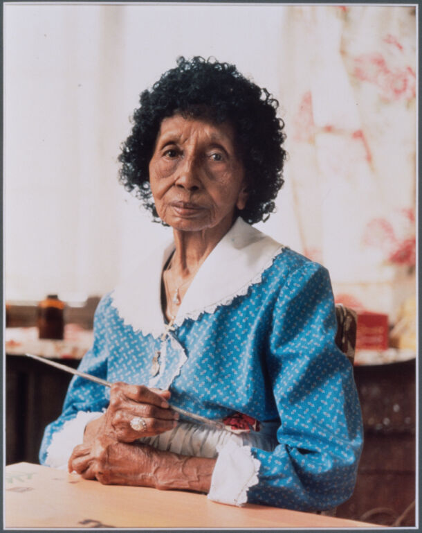 Portrait of Clementine Hunter holding a paint brush. 
