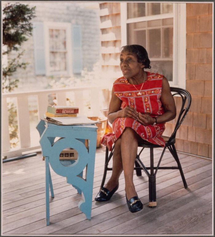 Portrait of Dorothy West sitting at her desk on her porch. 