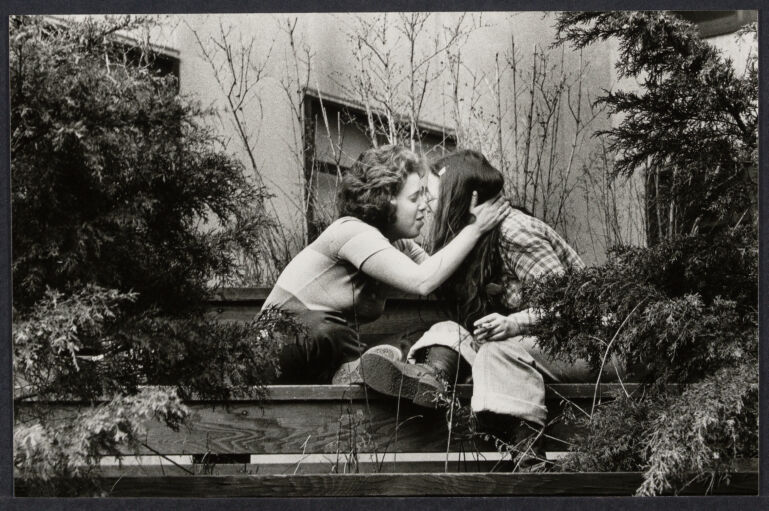 Two white women kissing amongst plants at  NYU campus
