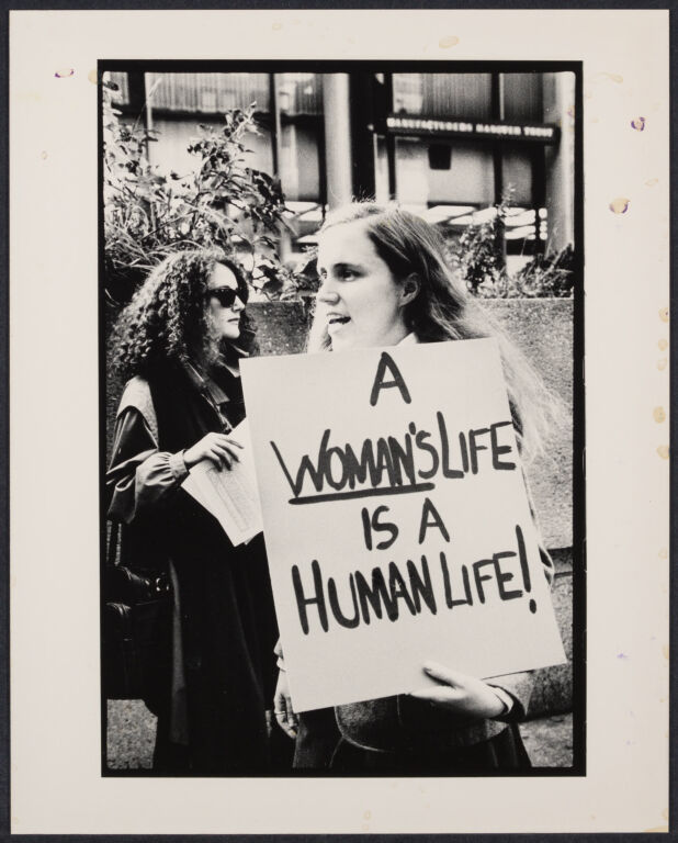 Photograph of a woman holding a poster reading "A woman's life is a human life"