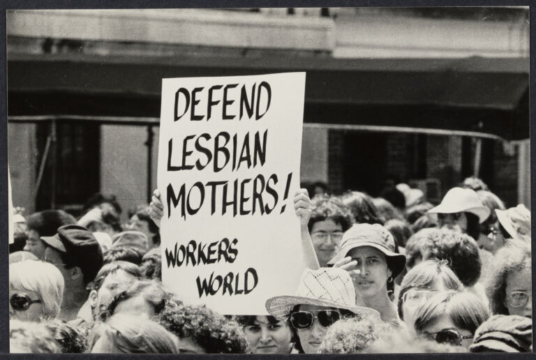 A protest march with one woman holding a sign that reads "Defend lesbian mothers! Workers World"