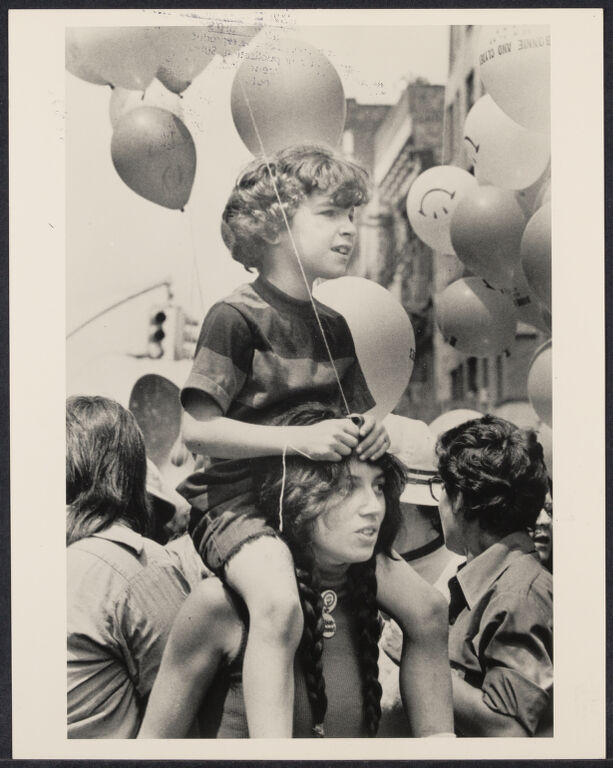 Child sitting on mother's shoulders holding a balloon