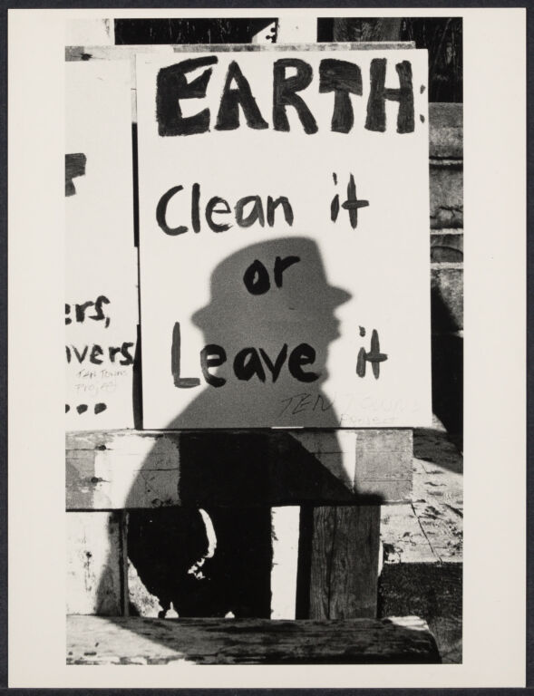 A poster that reads "Earth: Clean It or Leave It" with a person's shadow cast over it.