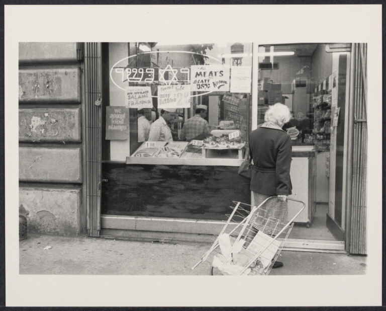 Woman pulling cart into a Jewish butcher shop